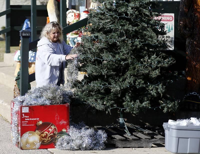 Karen Crocco decorates the Christmas tree in front of her shop, Karens Gift Shop, on Hancock Drive in Wonder Lake on Wednesday, Nov. 18, 2023. Plans are in the works for the Hancock Drive area of Wonder Lake to be annexed into the village.