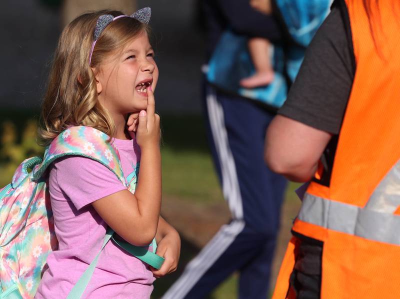 Avi Campbell, a second grader at Lincoln Elementary School, shows one of the teachers the teeth she lost over the summer as she arrives for her first day of classes Wednesday, Aug. 14, 2024, at the school in DeKalb.