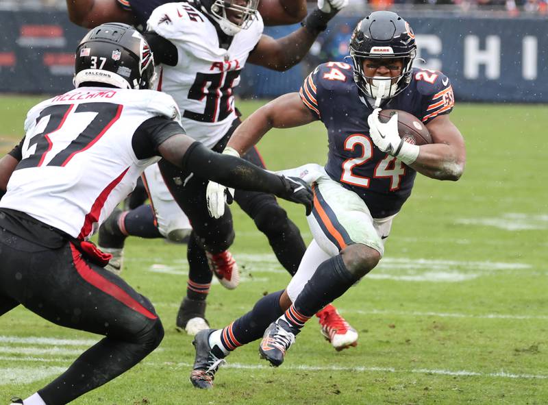 Chicago Bears running back Khalil Herbert looks to get by Atlanta Falcons safety DeMarcco Hellams during their game Sunday, Dec. 31, 2023, at Soldier Field in Chicago.