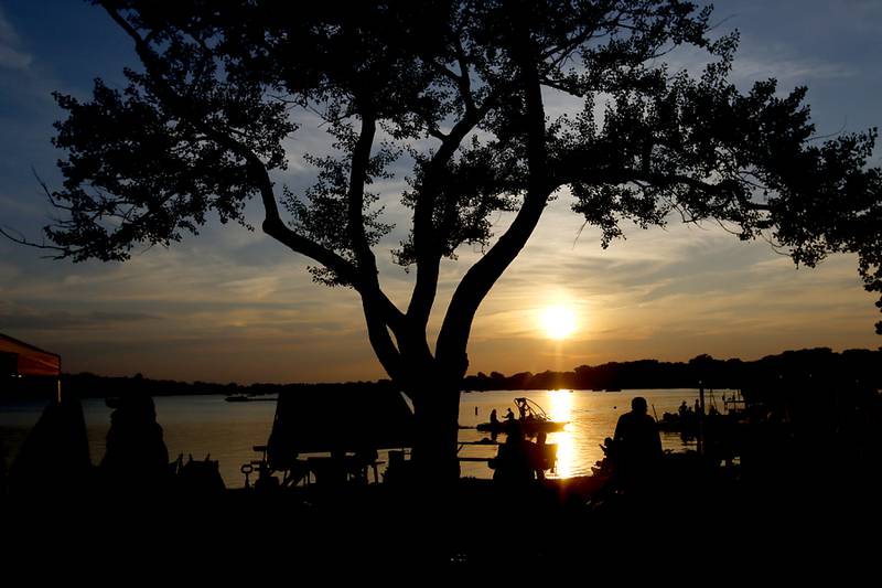 The sun sets over Crystal Lake as people wait for the fireworks show on Sunday, July 2, 2023, at Crystal Lake’s Main Beach during Crystal Lake Annual Independence Day Celebration.