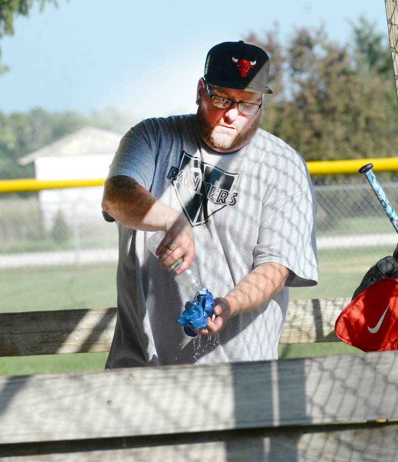Aaron Ardini pours water onto a kerchief to help keep him cool as he helps coach a Pony League softball action between Fulton and Erie-Prophetstown in Erie on Saturday, June 21, 2025.