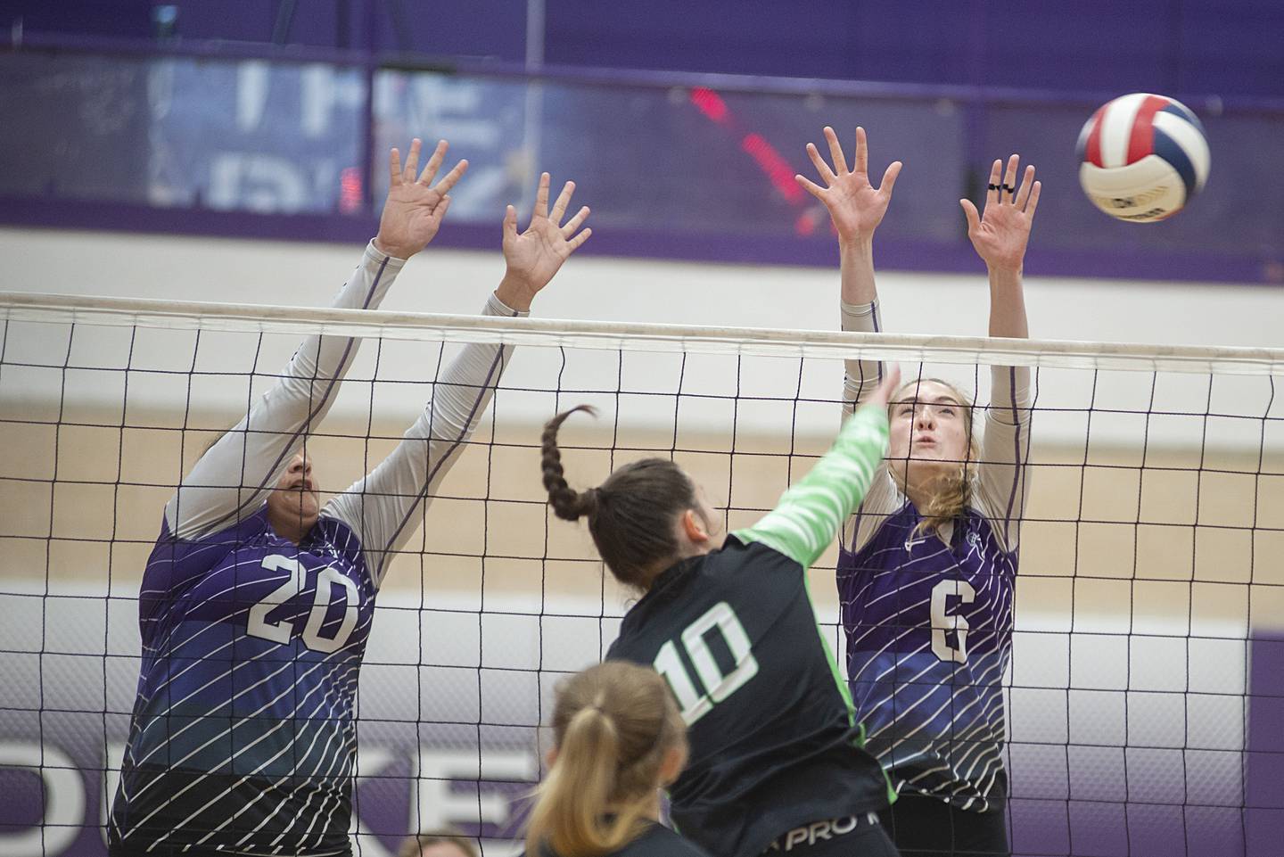 Dixon’s Olivia Cox (left) and Elexa Varden go up to block Alleman’s Iris Reynolds Wednesday, Sept. 7, 2022.