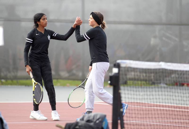 Fenwick doubles teammates Rachel Abraham (left) and Maeve Paris high-five during the first day of the IHSA state tennis tournament at Palatine High School on Thursday, Oct. 20, 2022.