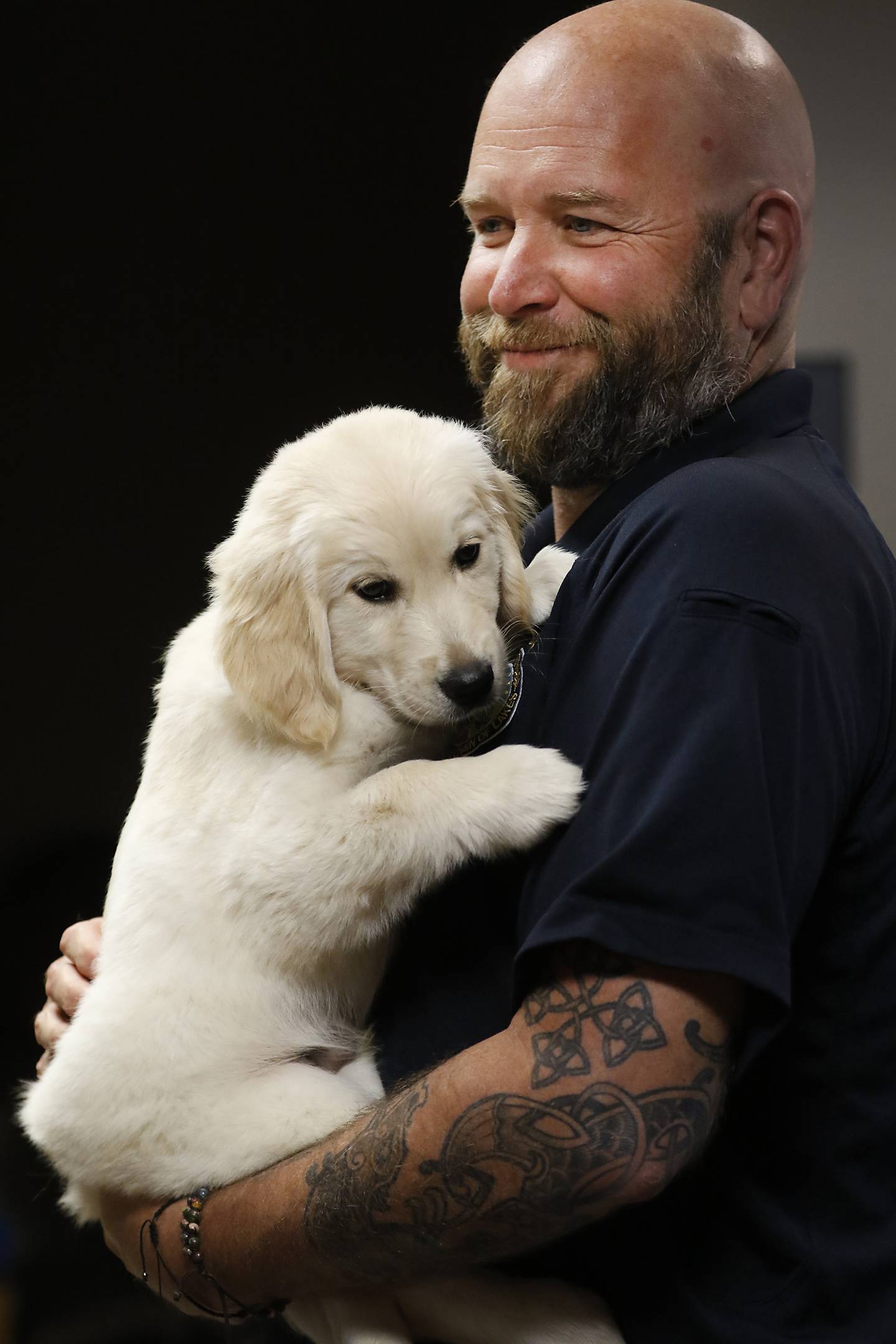 Le coordinateur des services sociaux du département de police de McHenry, Jason Stewerf, tient Oakley, le nouveau chien de thérapie du département de police de McHenry, le jeudi 4 août 2022, au département de police de McHenry.