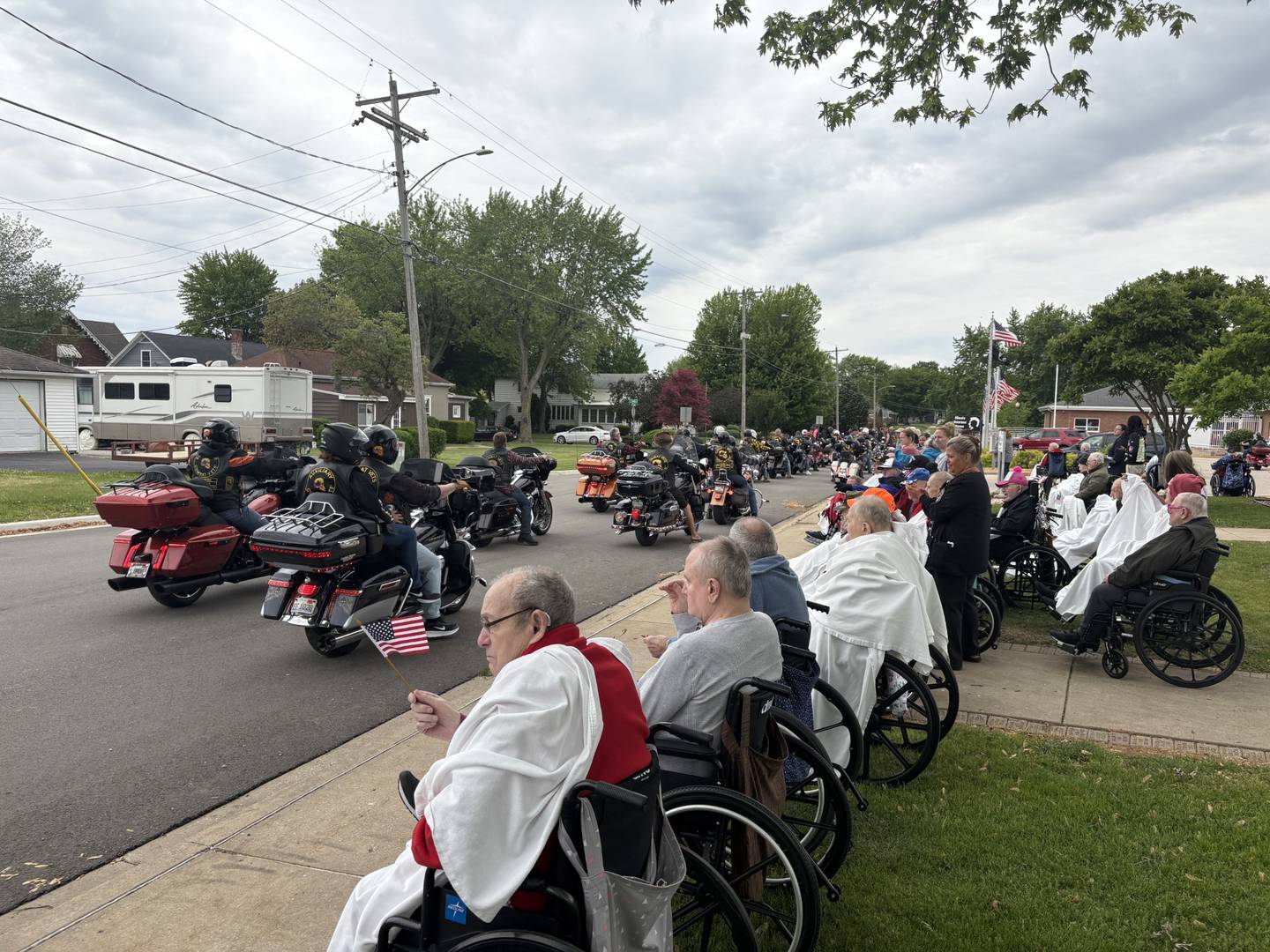 Residents and veterans line the street in front of the Illinois Veterans Home in La Salle, waving flags and welcoming members of the Combat Veterans Motorcycle Association as they arrive during their Memorial Day weekend ride on Saturday, May 24, 2025.