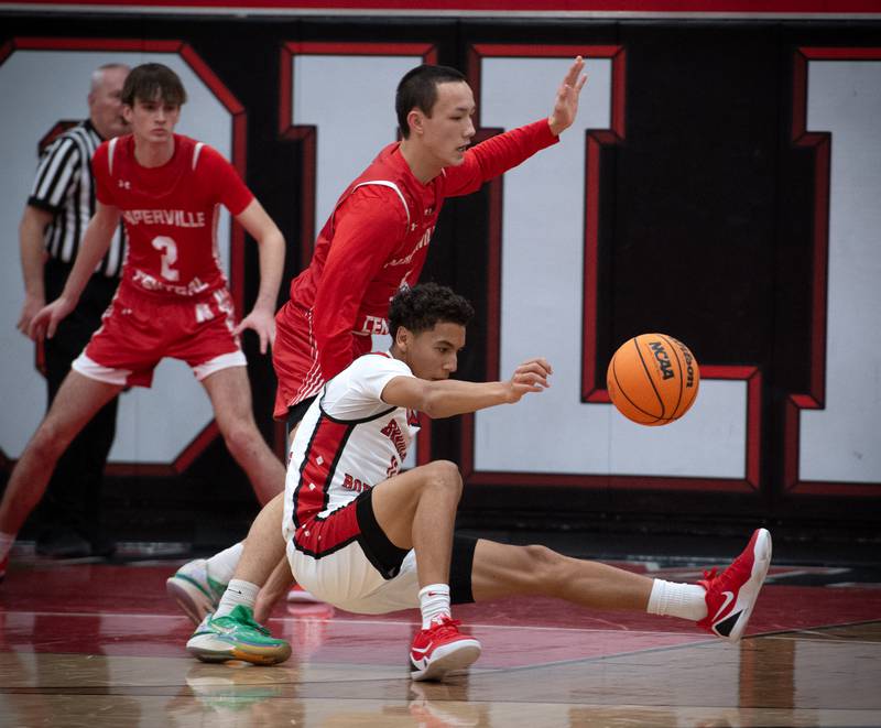Bradley-Bourbonnais's Trey Lawrence, front, loses his balance as Naperville Central's Liam Lau guards in a game on Monday, December 15, 2025.