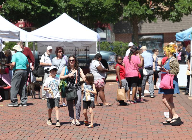 Attendees visit the tents during a very windy opening day at the DeKalb Farmers Market Thursday, June 6, 2024, at Van Buer Plaza in Downtown DeKalb. The market will run from 10 a.m. to 2 p.m. Thursdays through Sept. 19.