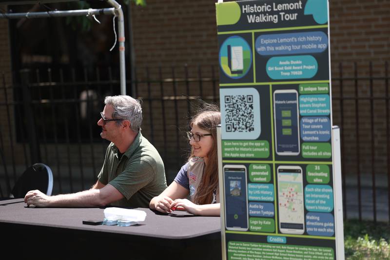 Amelia Dunkin, center, sits with her father, Mike, to promote her Girl Scouts Gold Award Project winning Historic Lemont Walking Tour app at the Lemont 150th Anniversary Commemoration on Friday, June 9, 2023 in downtown Lemont.
