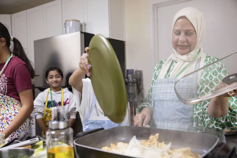 Shameem Syed, right, teaches students how to make a chicken stir fry during a cooking class at Olive Community Services, Tuesday, July 29, 2025, in Fullerton, Calif. The class was part of the organization's Intergenerational Summer Camp. (AP Photo/Zoë Meyers)