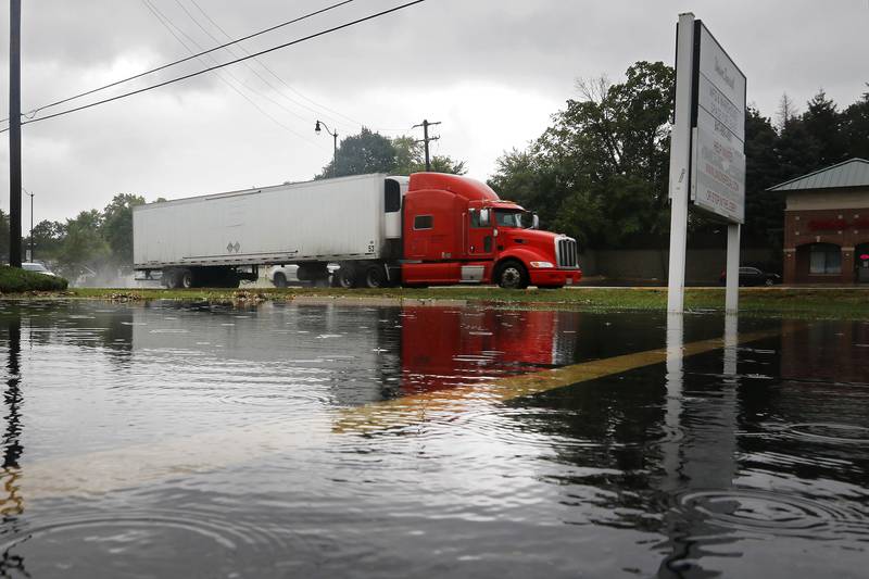 Vehicles travel along Route 47 as rain pours down, flooding a nearby parking lot on Monday, Aug. 9, 2021, in Huntley.
