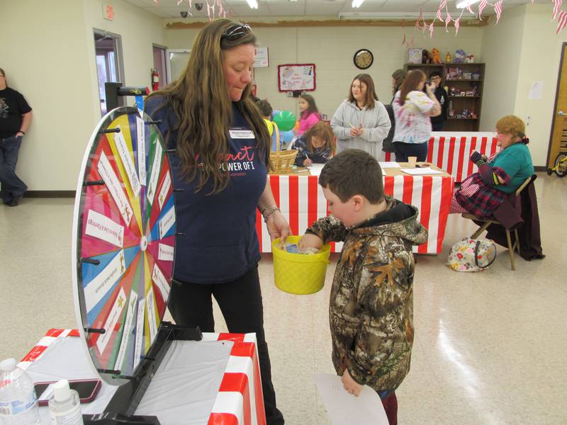 Raymon Roulston fishes for a prize Saturday, Nov. 12, 2022, during the Salvation Army's family fun fair in Ottawa. Shasta Hladovcak holds the prize bucket.