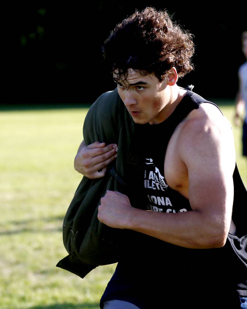 Cary-Grove’s Alex Schuppe runs with a weighted bag while doing conditioning drills during summer football practice Thursday, June 30, 2022, at Cary-Grove High School in Cary.