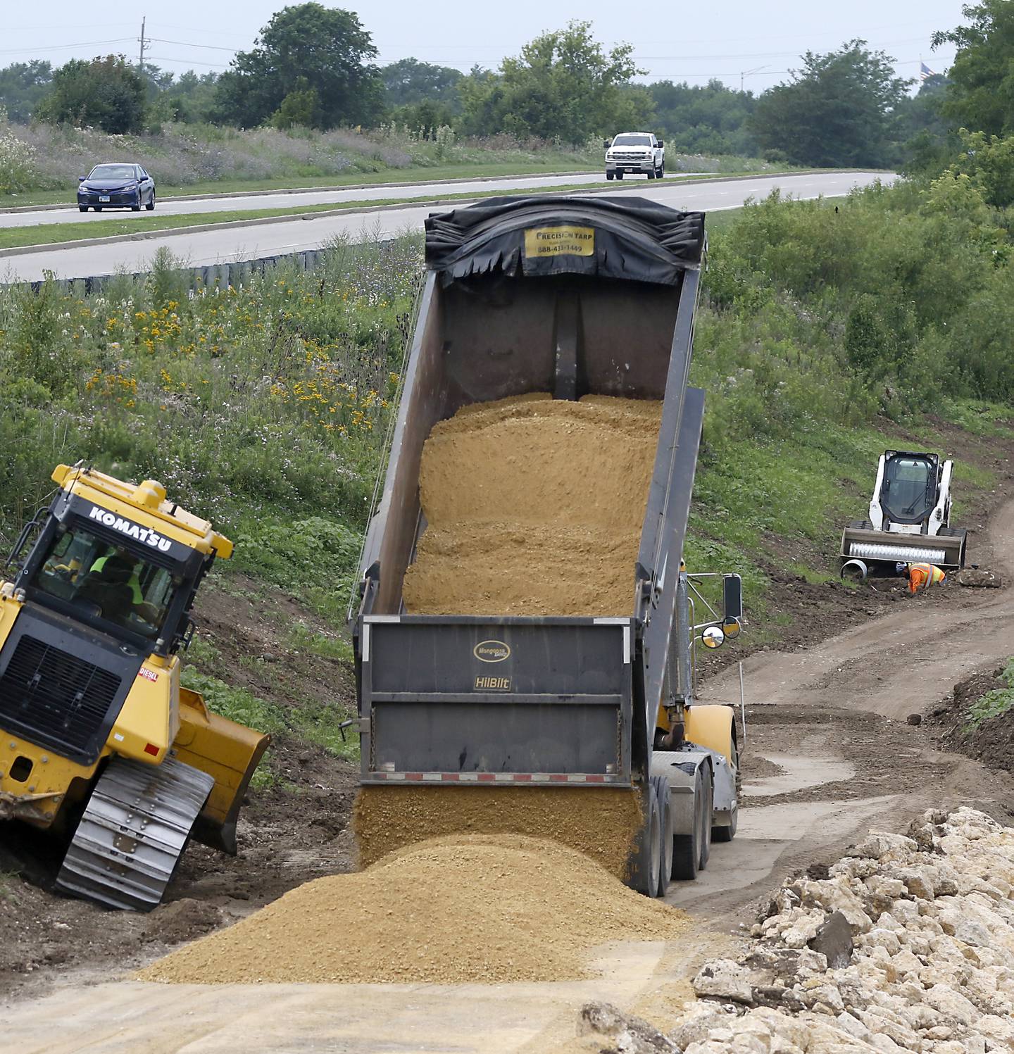 Work continues on a walking path around the lake at Three Oaks Recreation Area on Thursday, July 24, 2025, near the intersection of Pingree and James R. Rakow roads. When all the construction is complete there will be a 3.1 mile loop around the lake.