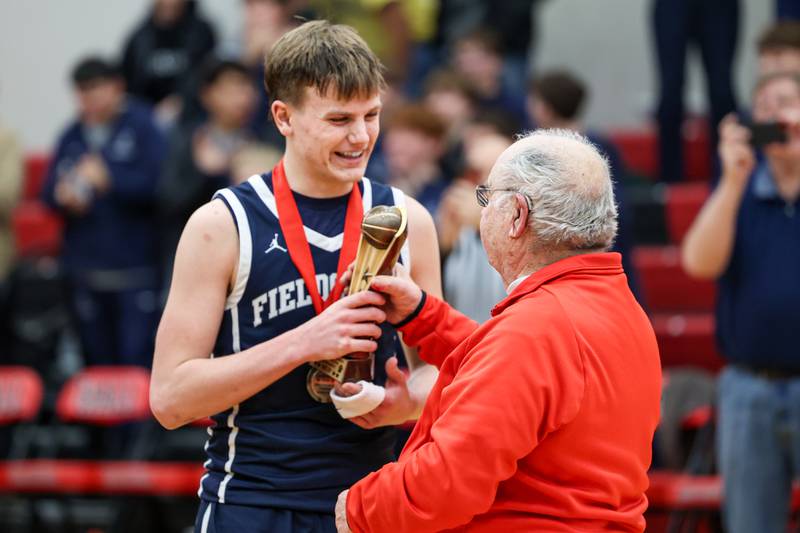 Eddie Lorton of Fieldcrest gets handed the tournament MVP trophy by Frank Colmone on Saturday, December 14, 2024 at Hall High School in Spring Valley.