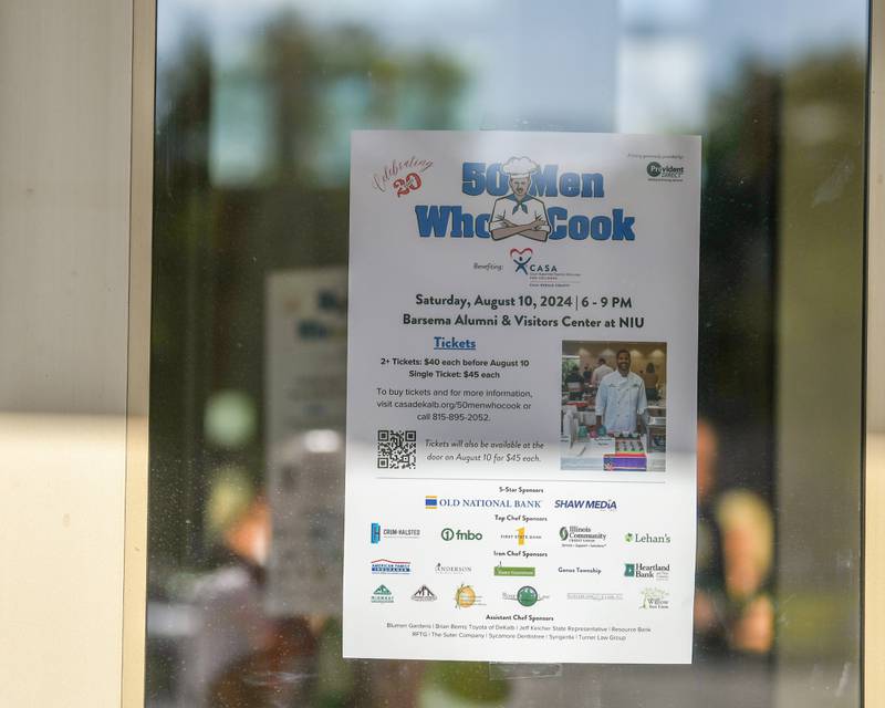 A flyer is taped on the door as people walked for the 20th anniversary of 50 Men Who Cook, an annual fundraiser hosted by CASA DeKalb County at the Barsema Alumni and Visitors Center at Northern Illinois University in DeKalb on Saturday, Aug. 10, 2024.