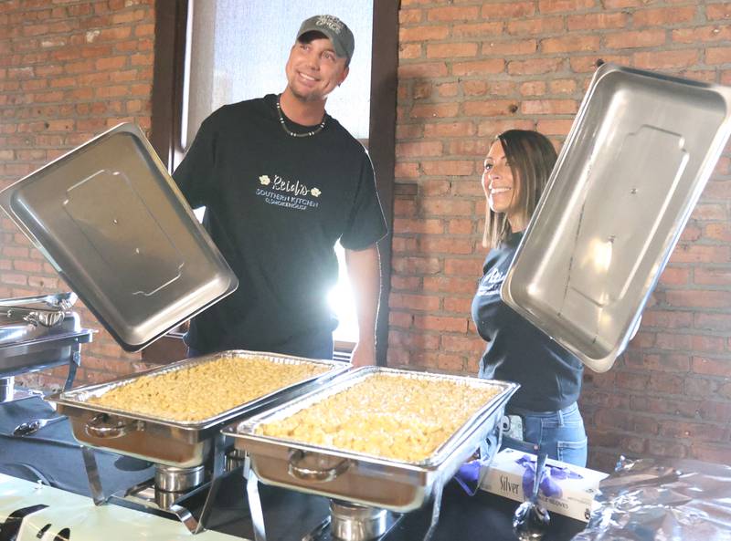 Richie Scott and Tessa Gonzalez of Reid's Southern Smokhouse, lift the lids off of their home made macroni and cheese during the WALLS 102 Listener Appreciation Party on Friday, May 8, 2026 at the Auditorium Ballroom in La Salle.