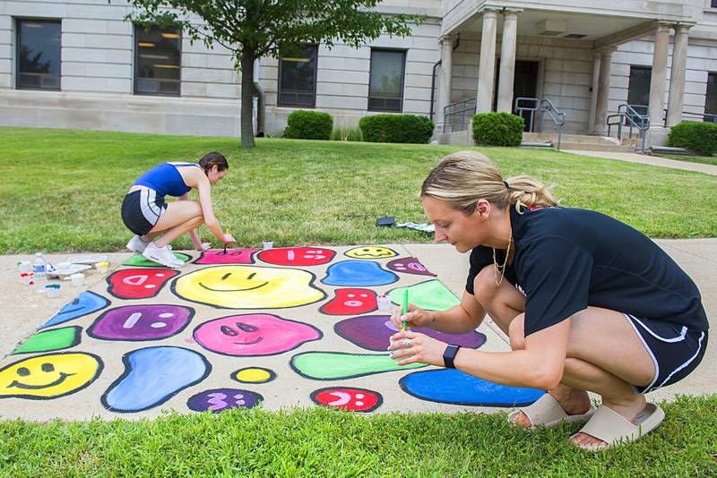 Shea Lahey (left) and sister Shannon add some color to their work of art Friday, July 1, 2022 during the Petunia Fest’s Brush and Bloom event at the old Lee County Courthouse.