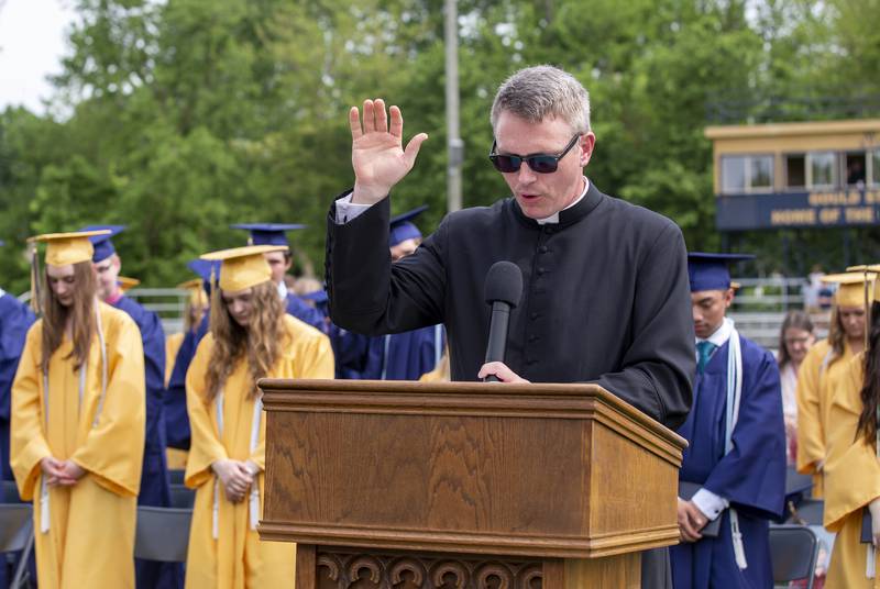 The Rev. Austin Bosse, school chaplain, gives a solemn blessing Sunday, May 29, 2022, at the conclusion of the Marquette Academy commencement ceremony at Gould Stadium.