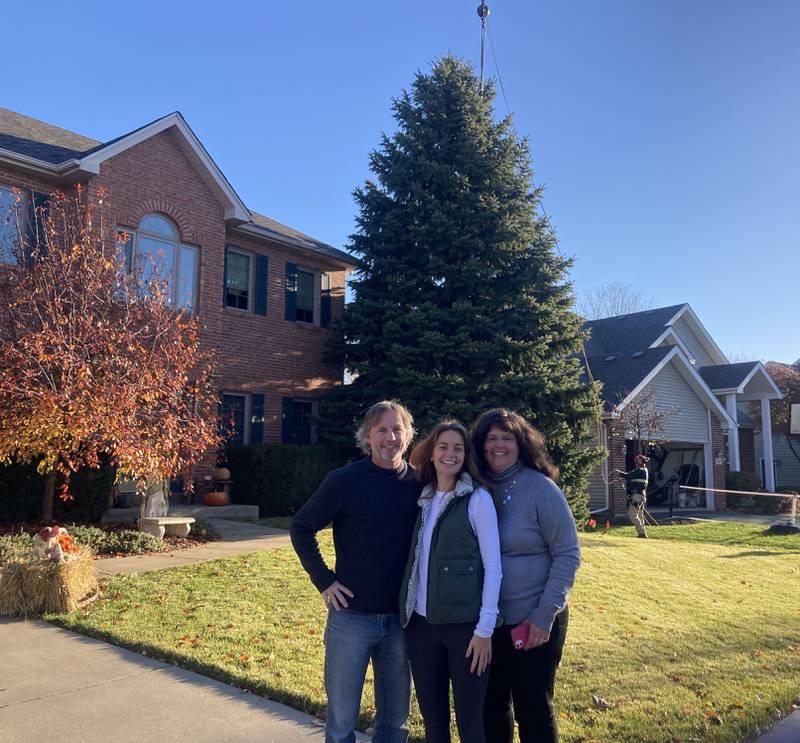 Dennis, Emma, and Amy Carter of Plainfield stand in front of their spruce tree while crews prepare to remove it for the City of Joliet to have as its official Christmas tree on Nov. 9, 2023.