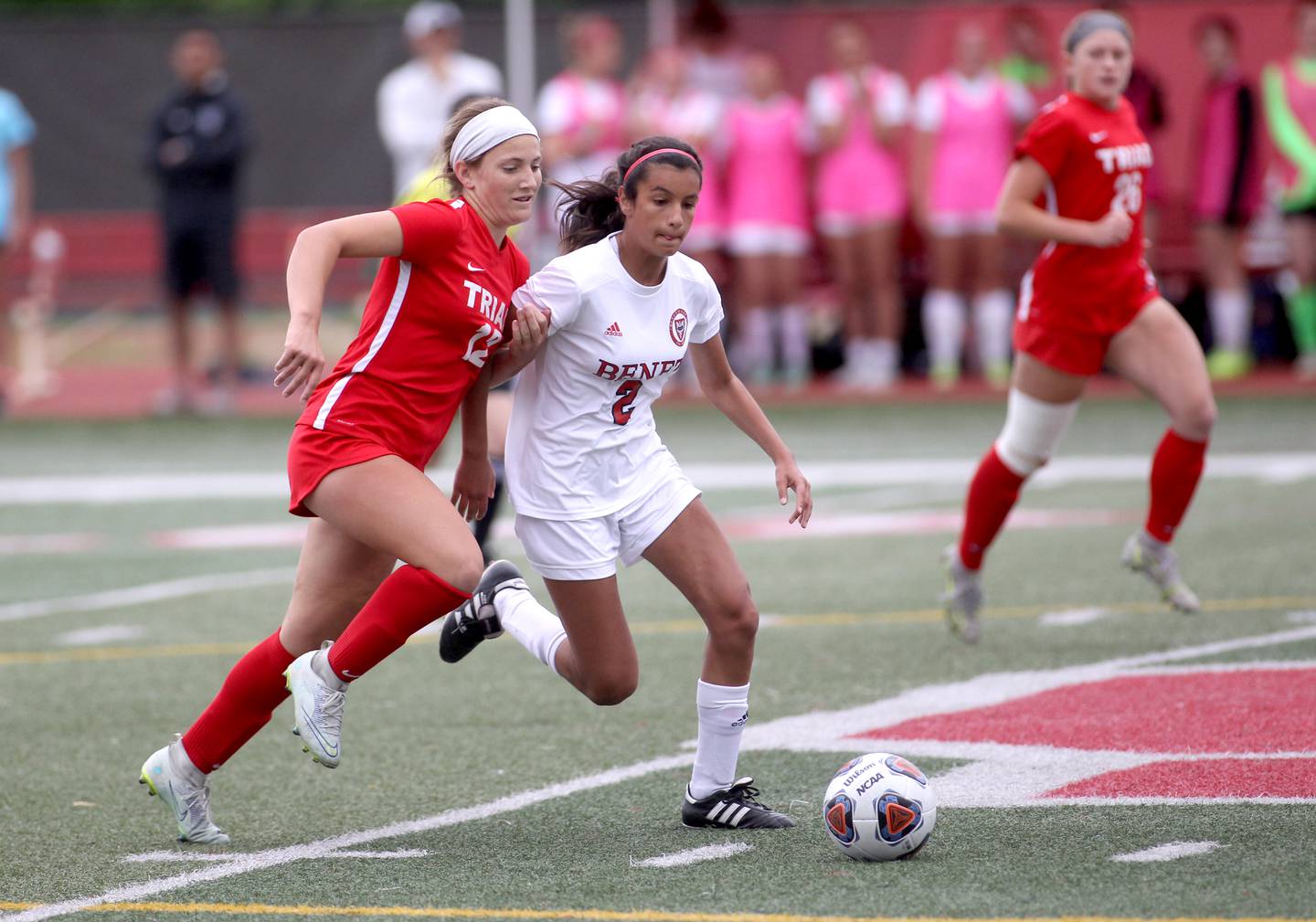 Triad’s Carson Bohnenstiehl (12) and Benet’s Rania Fikri (2) go after the ball during the IHSA Class 2A state championship game at North Central College in Naperville on Saturday, June 4, 2022.