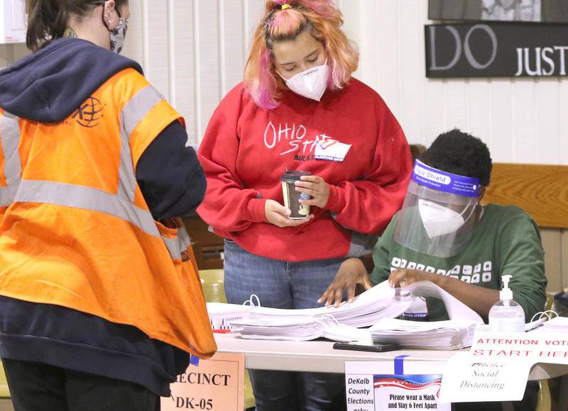 Khadija Nagi (left) and Gaelle Grace get voters checked in Tuesday at the polling place inside the Westminster Presbyterian Church on Annie Glidden Road in DeKalb.