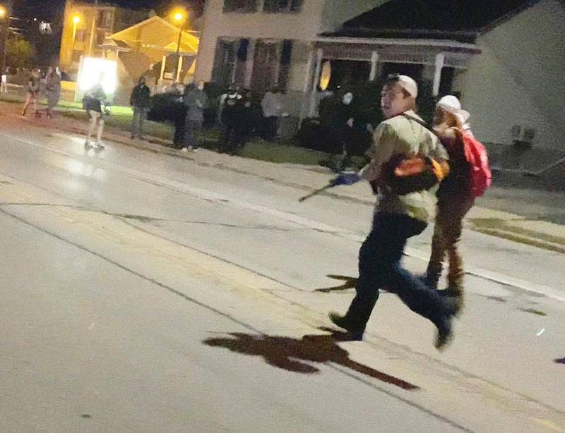 Kyle Rittenhouse of Antioch runs down a street while holding a long gun Aug. 26 in Kenosha, Wis. He is accused of shooting three people, killing two of them.