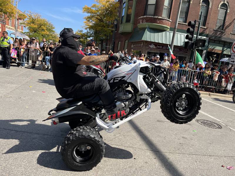 An ATV rider popping a wheelie while participating in the 60th annual Mexican Independence Day parade on Saturday, Sept. 23, 2023, in downtown Joliet.