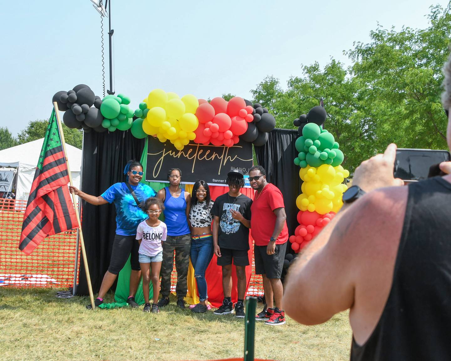 Family members Dymond, 7, Jasmine, Karia, Malaika Bryan, 16, and Paul Rollins hold A Pan-African flag and pose in front of a Juneteenth backdrop at the entrance of the 3rd annual Juneteenth celebration held in Plano at Emily G. Johns School on Saturday June 17, 2023.