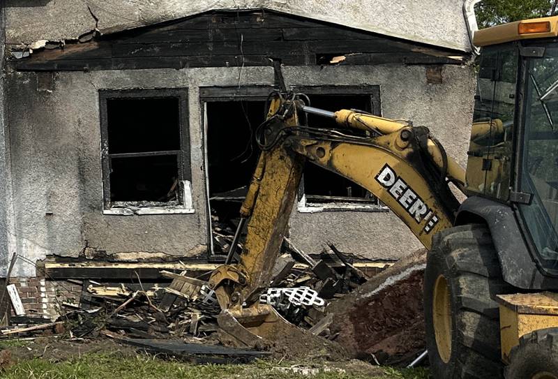 A backhoe begins to demolish the front porch of a home located in the 800 block of Bucklin Street on Thursday, May 7, 2026 in La Salle. The home was destroyed by a fire on Jan. 23. Firefighters worked together to battle the blaze in subzero temperatures.