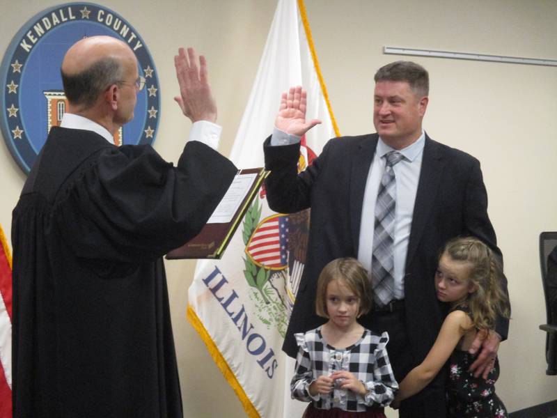 Matt Kellogg takes the oath of office for a new term on the Kendall County Board from Judge Stephen Krentz, with daughters Morgan, 5, and Maya, 6, right. Kellogg was elected the new board chairman by his peers on Dec. 5, 2022.