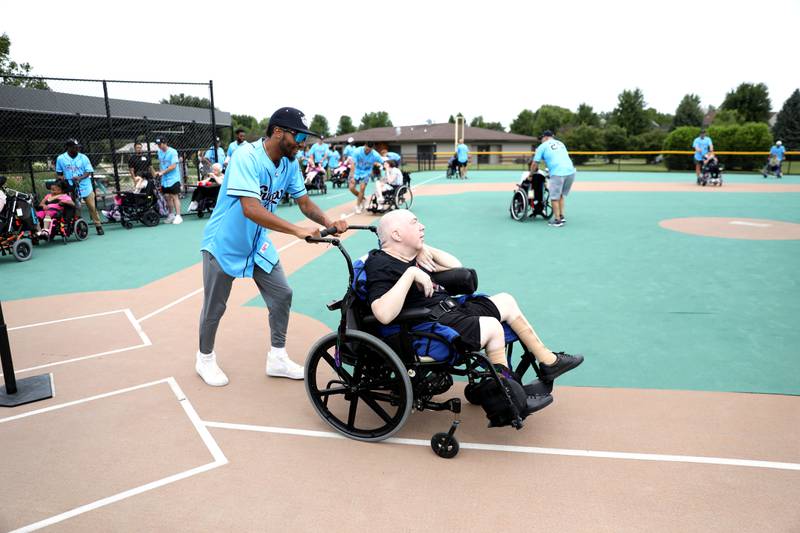 Kane County Cougars pitcher Michael Brewer runs to first base with Marklund client Mike during a softball game at Marklund Hyde Center in Geneva on Tuesday, July 9, 2024.