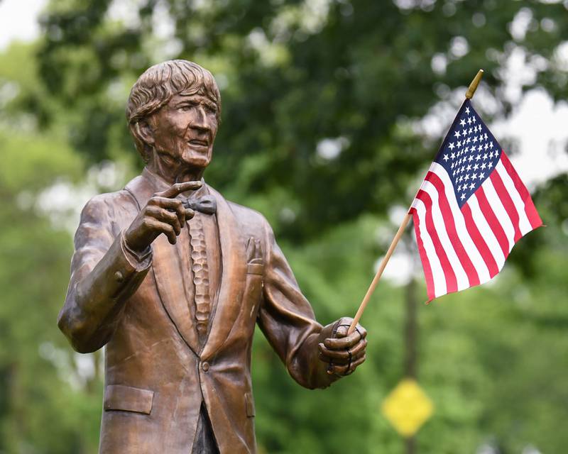 A statue of W. "Dee" Palmer, the former director of the DeKalb Municipal Band, holds an American flag at Hopkins Park in DeKalb on Monday July 4, 2022 to celebrate the Fourth of July.