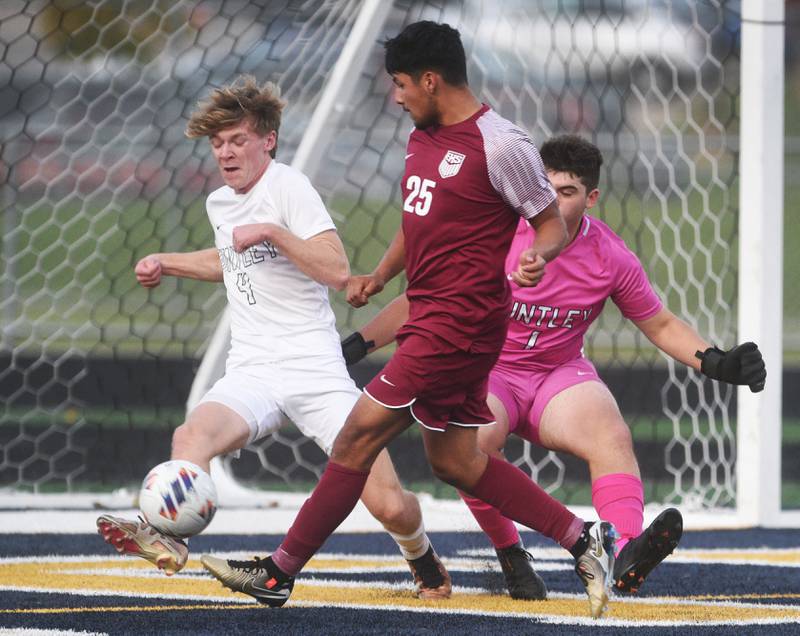 Elgin's Eduardo Nava (25) moves the ball past Huntley's Brandon Foster (4) and goalkeeper Jeremmiah Reynolds before making his second goal during Tuesday’s IHSA class 3A sectional semifinal boys soccer game in Round Lake.