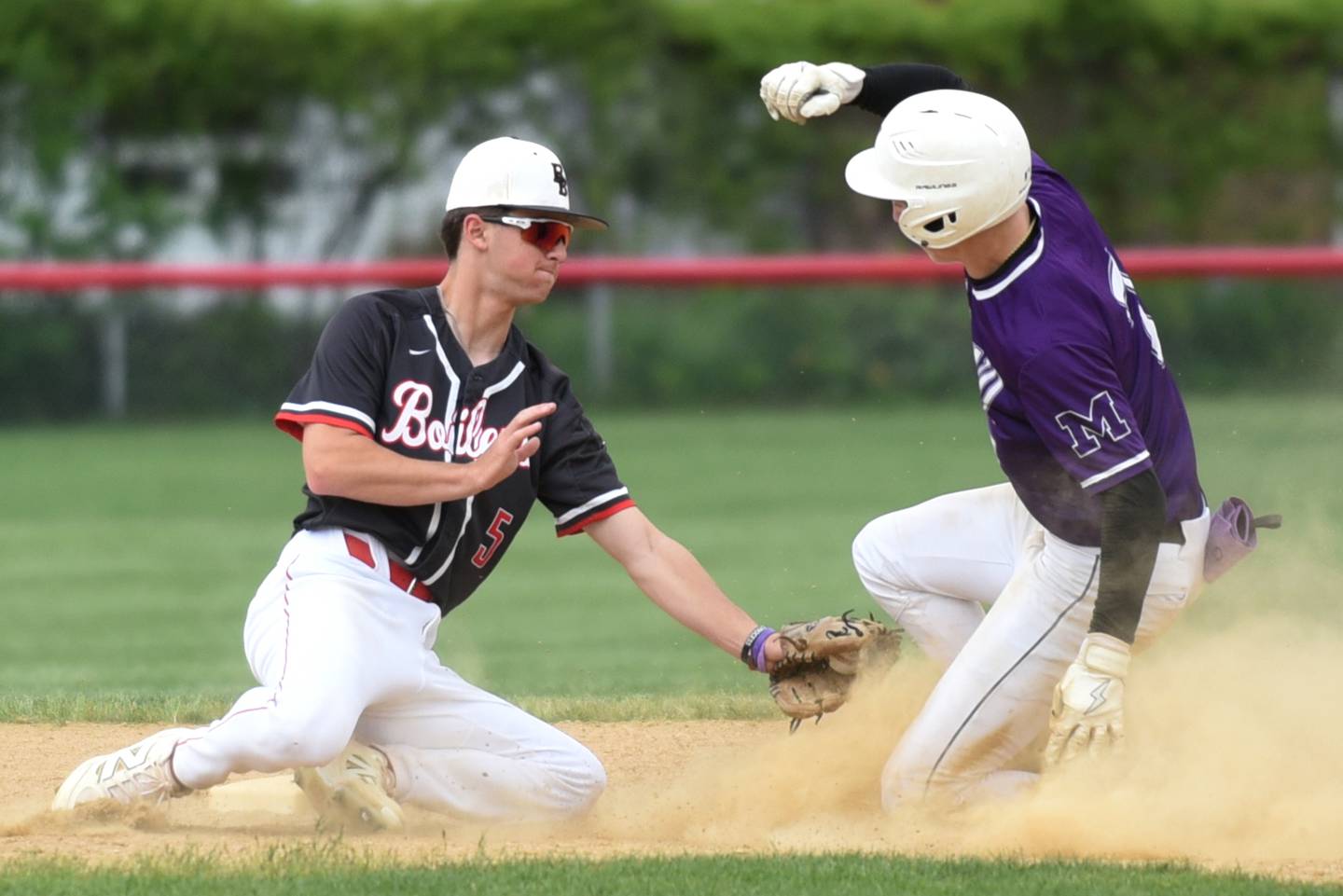 Bradley-Bourbonnais' Jace Boudreau, left, reaches to tag Manteno's Quinn Borden during a game at Bradley-Bourbonnais Saturday, May 17, 2025.