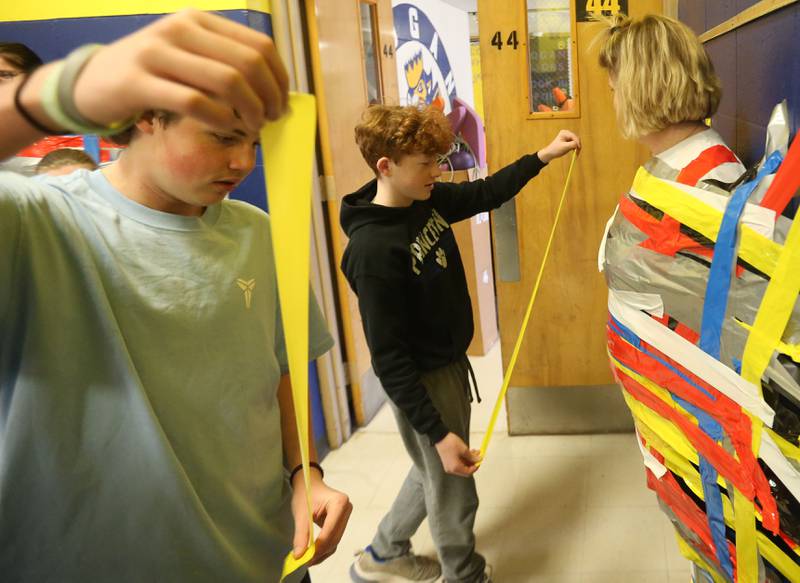 Students Kip Cook and Collin Deever places strips of duct tape on Rebecca Shepherd. Sixth Grade Social Studies during the "Tape The Teacher" fundraiser on Friday, March 20, 2026 at Logan Jr. High School in Princeton.