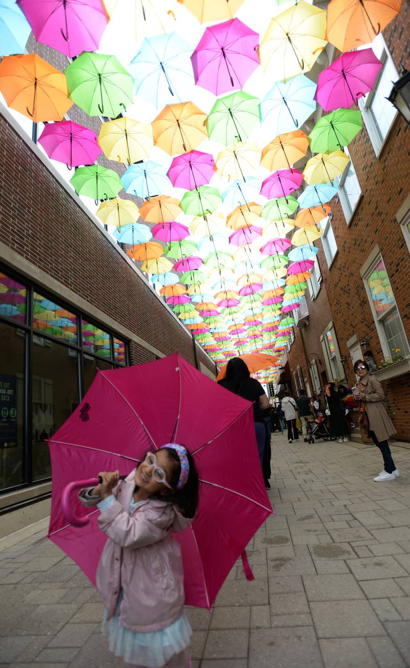 Children including Lana Doshi of Elmhurst pose for pictures using umbrellas as props at Schiller Court during the Public Art Commission's Umbrella Sky Project Opening Day Party held Saturday April 29, 2023.