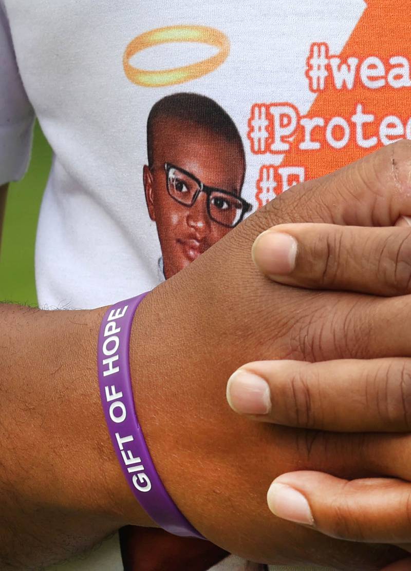 Brandon Elion, stepfather of Ezra Hill Jr., wears a gift of hope bracelet and a stop gun violence shirt with Ezra’s photo on it as he and Ezra’s mom Andrea Harden talk about him Monday, May 12, 2025, at Tyler Elementary School. Hill was murdered in 2019 in Harvey, and the Fifth Annual Ezra Hill Jr. Memorial Rock Painting event will be held on June 7 at the school in DeKalb.