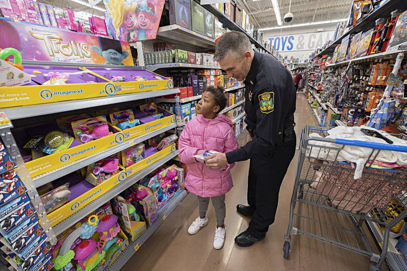 Polo officer Tim Rockwood checks out a selection from Saniyah Davis, 8, while participating Saturday, Dec. 9, 2023 in Shop with a Cop at the Dixon Walmart.