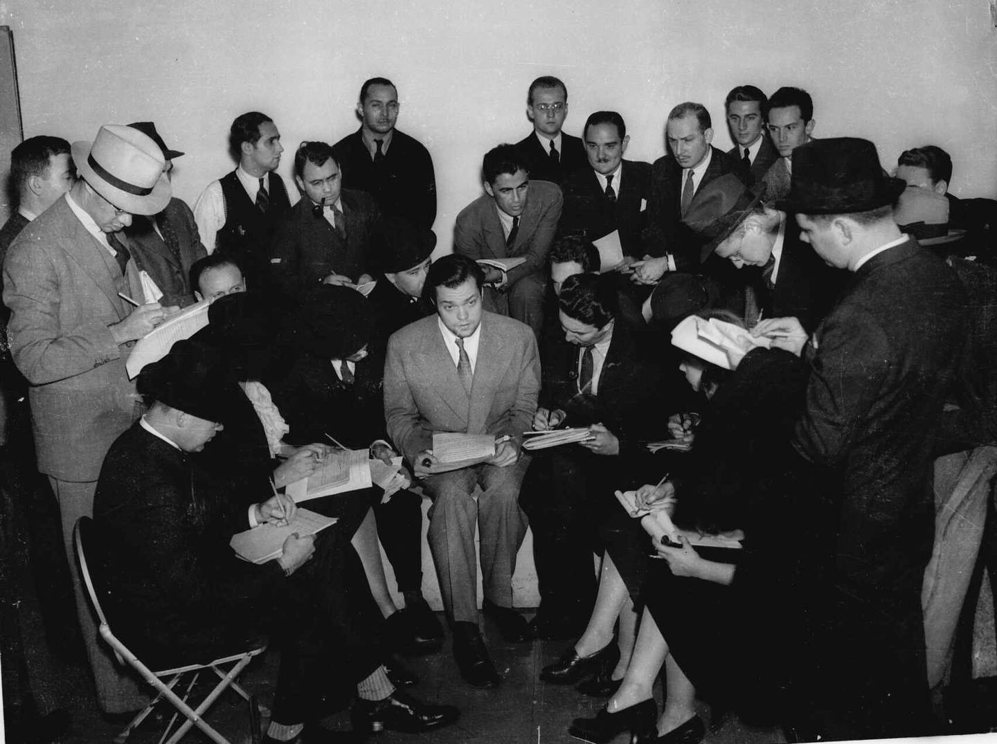 Orson Welles (center), the young director who presented the dramatization of H.G. Wells' "The War of the Worlds" on Oct. 30, 1938, speaks with the press the next day.  The radio broadcast caused great panic among radio listeners amazed that his dramatization had been so realistic.
