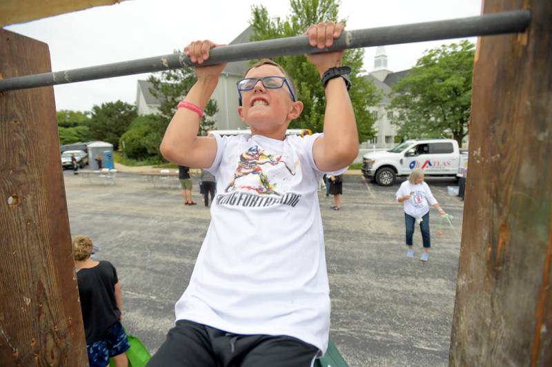 Reed Gerhart, 10 of St Charles tries out the pull-up bar at the Boy Scout of America Troop 46 booth during Campton Hills National Night Out on Tuesday, August 6, 2024.