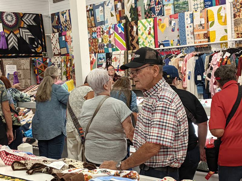 During the opening day of the Sandwich Fair on Sept. 4, 2024, people check out the homemade quilts on display in the Home Arts Building.