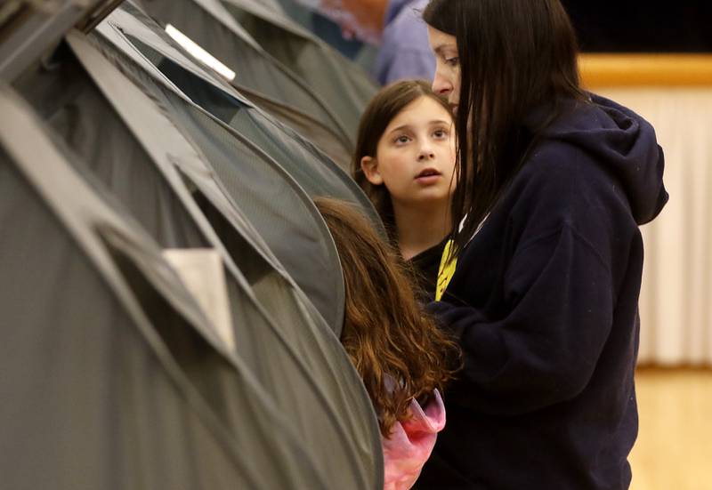 Alexa Hoving, 7, of Hampshire, (left) and her sister, Julia, 11, (center) watch as their mother, Katie, casts her vote Tuesday, April 4, 2023, in the 2023 consolidated election at Del Webb Sun City’s Prairie Lodge in Huntley.
