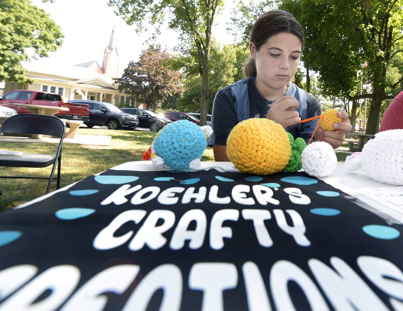 Faith Koehler creates another crafty creation with yarn at her business table Saturday at Washington Park in Ottawa during the 4th annual Children’s Business Fair.