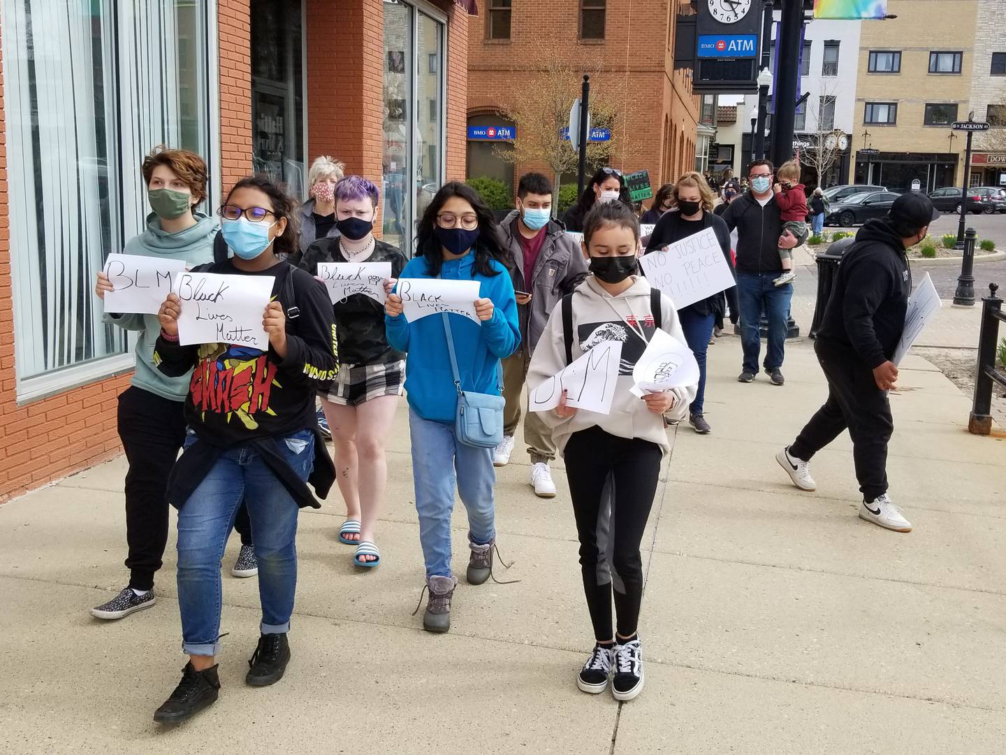Alex Guzman, front left, was among about 40 people who marched around downtown Woodstock's Historic Square on Sunday, April 18, 2021, to protest violence by police officers against immigrants and indigenous people and people of color in the country.