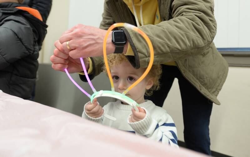 Children including Peter Salawa of Downers Grove get assistance making bunny ears during the Downers Grove Bunny Hop Egg Hunt Friday, March 22, 2024.