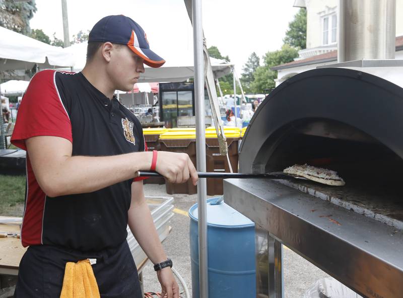 Tim Bragdon of Kissed By Fire BBQ & Pizza puts a pizza in the oven Friday, July 1, 2022, during Lakeside Festival at the Dole and Lakeside Arts Park, 401 Country Club Road in Crystal Lake. The festival continues noon to 11 p.m. July 2 and noon to 10 p.m. July 3. The festival features bands on two outdoor stages, food and drinks, a baggo tournament, and carnival rides and games. Among the activities for kids are face painting, a balloon twister, a stilt walker, team mascots and a magician.