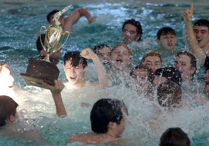 Swimmers from Cary-Grove co-op celebrate with the trophy after winning the Fox Valley Conference Swimming Championships at Woodstock North High School Saturday.