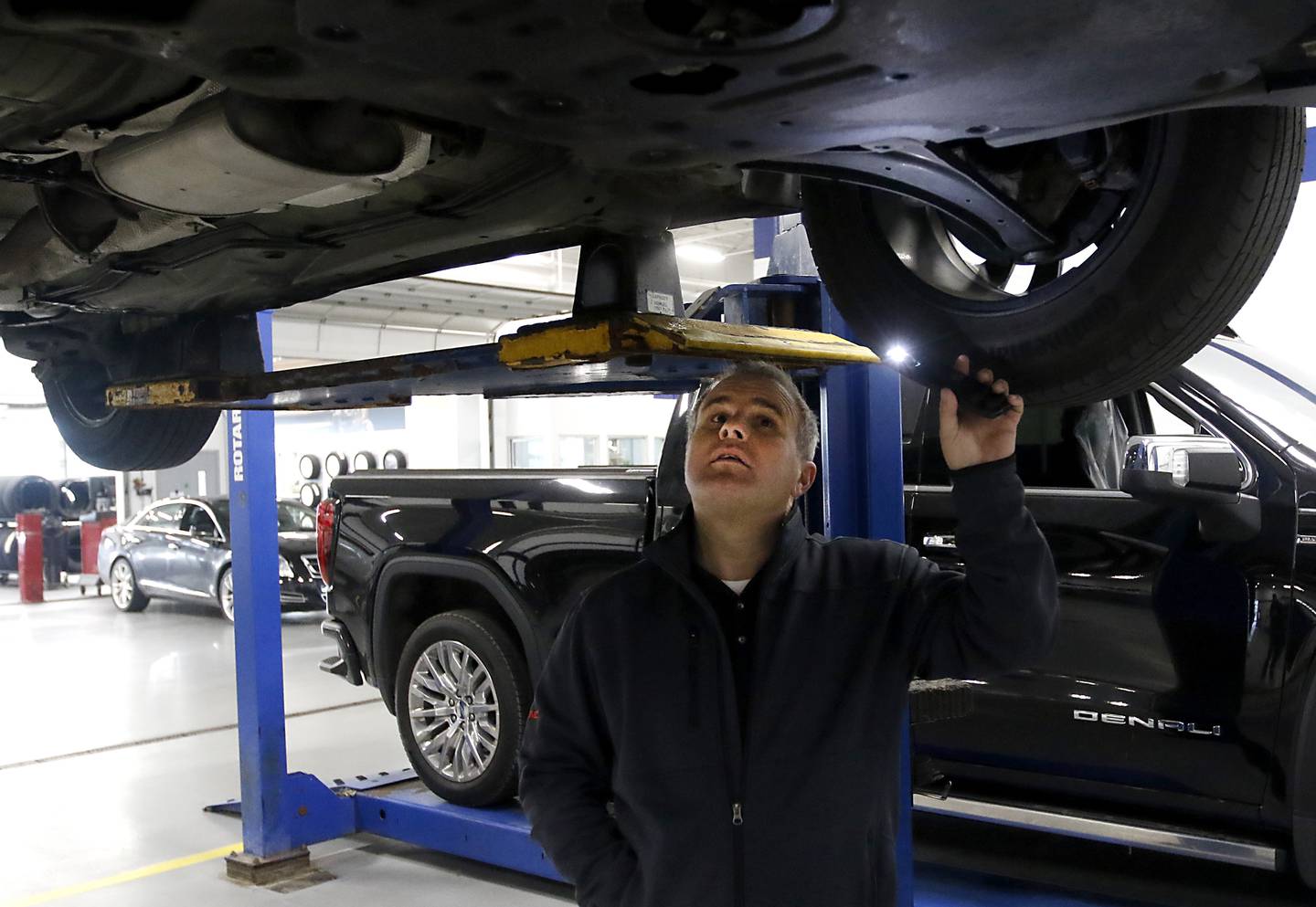 Ryan Miller, the used vehicle director at Castle AutoPlex, inspects the underside of a car Thursday, Dec. 8, 2022, at Castle AutoPlex, 1107 Route 31, in McHenry. Castle, which purchased the former Gary Lang dealership earlier this year, is looking to add two more buildings to the campus in the next couple of years for import brands.