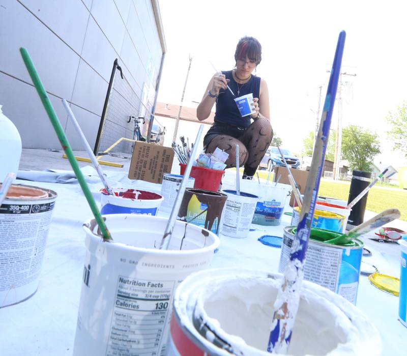 Jay McConnil mixes paint to draw a mural on an exterior wall on Tuesday, May 23, 2023 at Nicks on 6 in La Salle.