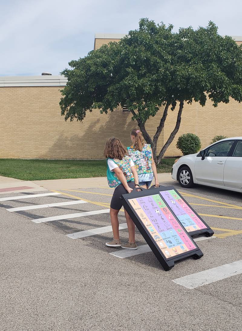 Girl Scouts from McHenry Troop 360 roll the A-frame communications signs to each of the two playgrounds at Edgebrook Elementary School on Monday, Aug. 15, 2022.